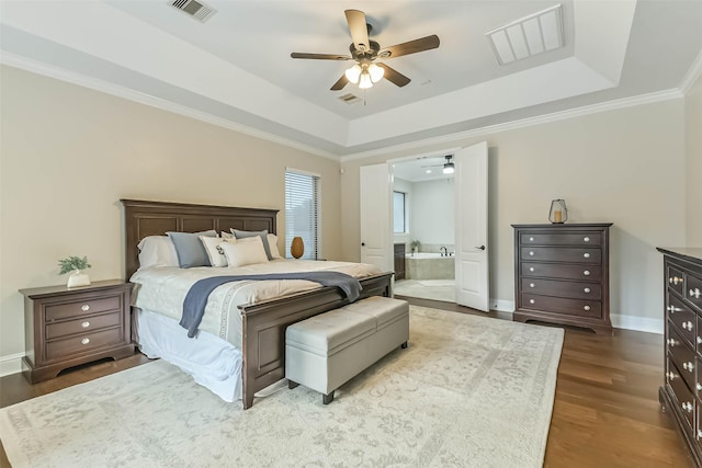 bedroom with ensuite bathroom, visible vents, a raised ceiling, and dark wood finished floors