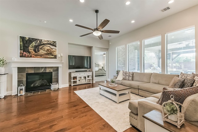 living area with recessed lighting, a tiled fireplace, a ceiling fan, visible vents, and wood finished floors