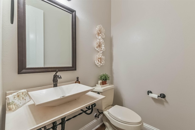 bathroom with baseboards, toilet, and a sink