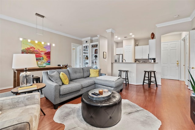 living room featuring recessed lighting, wood finished floors, crown molding, and built in shelves