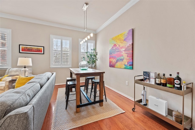 dining area with baseboards, crown molding, and wood finished floors