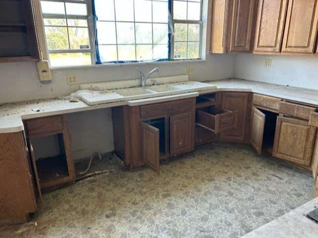 kitchen with open shelves, light countertops, a sink, and brown cabinets