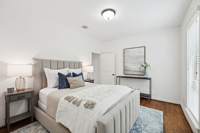 bedroom featuring baseboards, wood finished floors, and visible vents