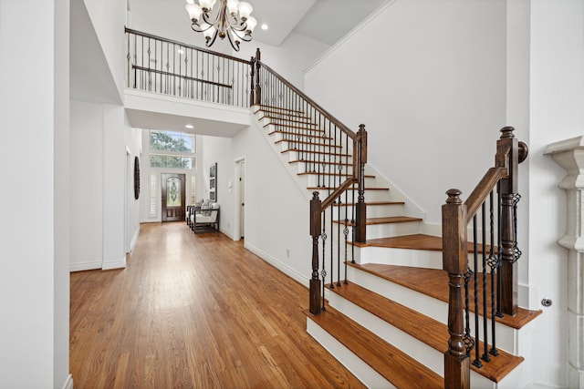 entrance foyer featuring an inviting chandelier, wood finished floors, baseboards, a high ceiling, and stairway