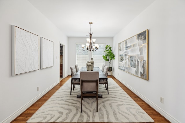 dining area with dark wood-style flooring, baseboards, and an inviting chandelier