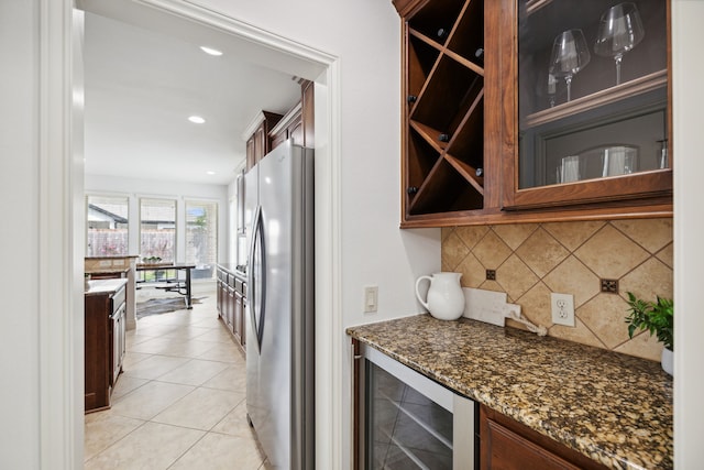 bar with decorative backsplash, a dry bar, light tile patterned floors, freestanding refrigerator, and beverage cooler