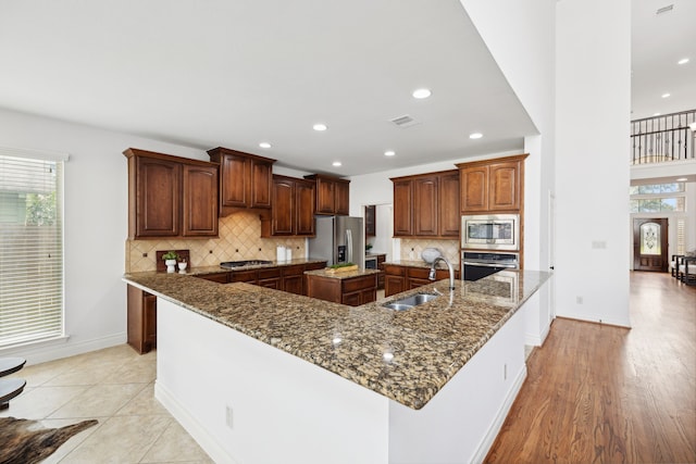 kitchen featuring a large island with sink, a sink, plenty of natural light, and appliances with stainless steel finishes