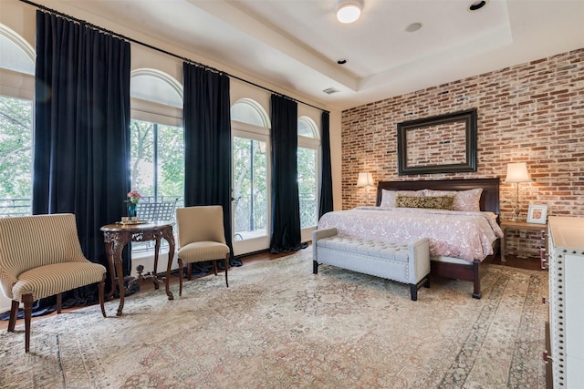 bedroom with a tray ceiling, multiple windows, visible vents, and brick wall