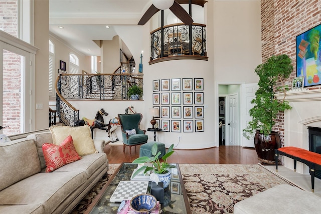 living room featuring a glass covered fireplace, wood finished floors, stairs, and a high ceiling