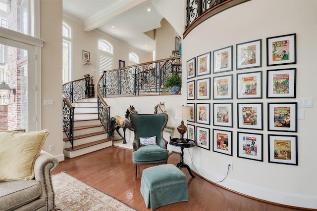 living area with baseboards, wood finished floors, stairs, and ornamental molding