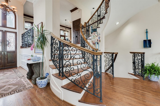 foyer featuring a towering ceiling, stairs, french doors, and wood finished floors