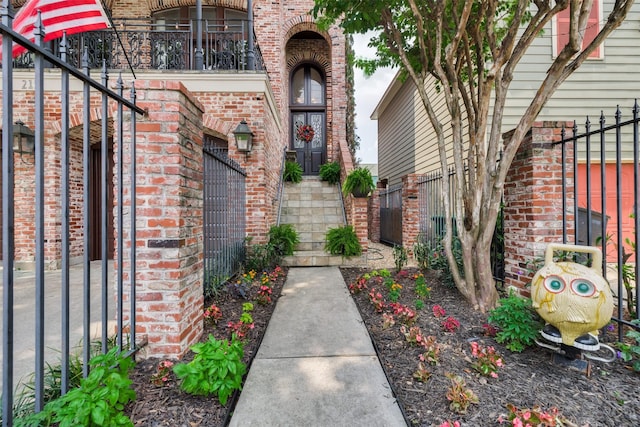 doorway to property featuring fence, a balcony, and brick siding