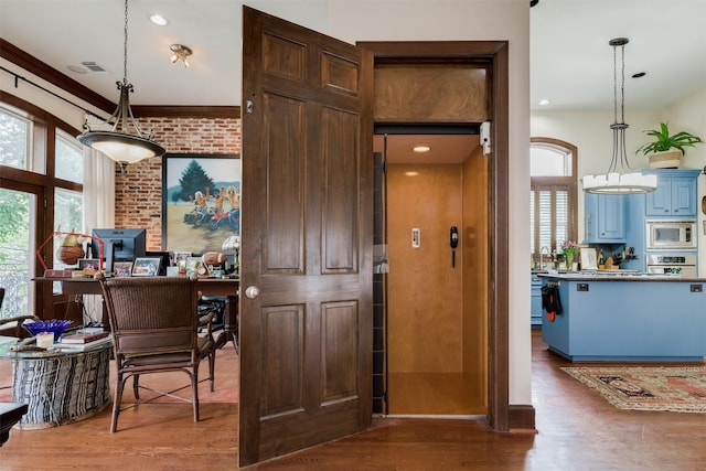 interior space featuring blue cabinetry, visible vents, pendant lighting, appliances with stainless steel finishes, and wood finished floors