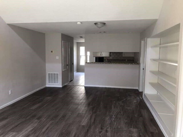 811 Buchta Rd Unit C, Angleton, TX 77515 - unfurnished living room with visible vents, baseboards, and dark wood-style flooring