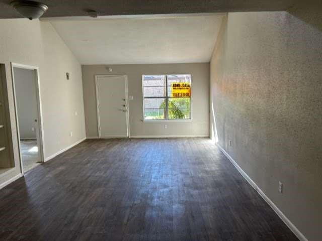 811 Buchta Rd Unit C, Angleton, TX 77515 - unfurnished living room featuring dark wood finished floors, vaulted ceiling, and baseboards