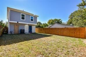rear view of house with a fenced backyard and a yard