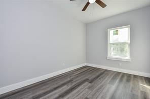 empty room with a ceiling fan, baseboards, and dark wood-style flooring