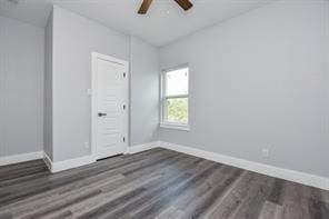 spare room featuring dark wood-style flooring, baseboards, and ceiling fan
