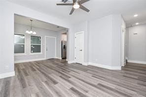 unfurnished living room with recessed lighting, baseboards, wood finished floors, and ceiling fan with notable chandelier
