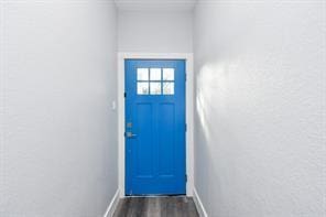 doorway featuring baseboards and dark wood-style flooring