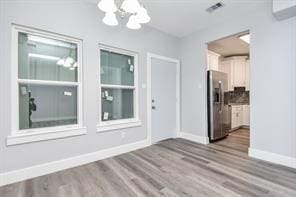 interior space with an inviting chandelier, wood finished floors, and baseboards