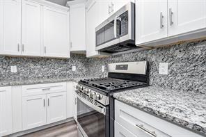 kitchen featuring white cabinets, decorative backsplash, appliances with stainless steel finishes, and light stone counters