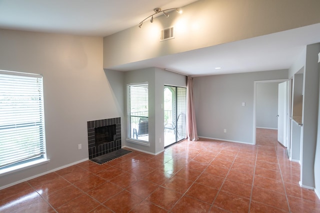 2025 Augusta Dr Unit 208, Houston, TX 77057 - unfurnished living room with tile patterned floors, rail lighting, visible vents, baseboards, and a brick fireplace