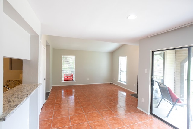 2025 Augusta Dr Unit 208, Houston, TX 77057 - unfurnished living room with lofted ceiling, baseboards, and light tile patterned floors