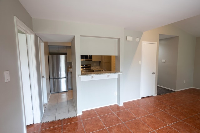 2025 Augusta Dr Unit 208, Houston, TX 77057 - kitchen featuring stainless steel appliances, a peninsula, tile patterned floors, gray cabinets, and light stone countertops