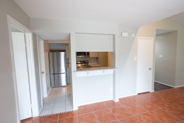 2025 Augusta Dr Unit 208, Houston, TX 77057 - kitchen featuring light tile patterned floors, a peninsula, baseboards, appliances with stainless steel finishes, and light stone countertops