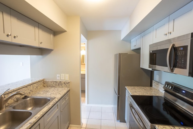 2025 Augusta Dr Unit 208, Houston, TX 77057 - kitchen featuring light stone countertops, stainless steel appliances, a sink, baseboards, and light tile patterned flooring