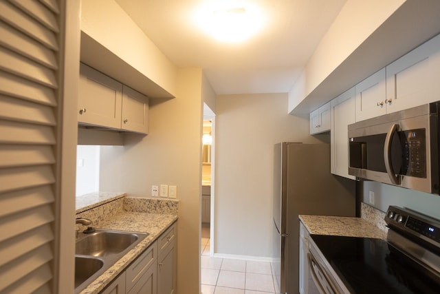 2025 Augusta Dr Unit 208, Houston, TX 77057 - kitchen with light tile patterned floors, light stone counters, a sink, and appliances with stainless steel finishes
