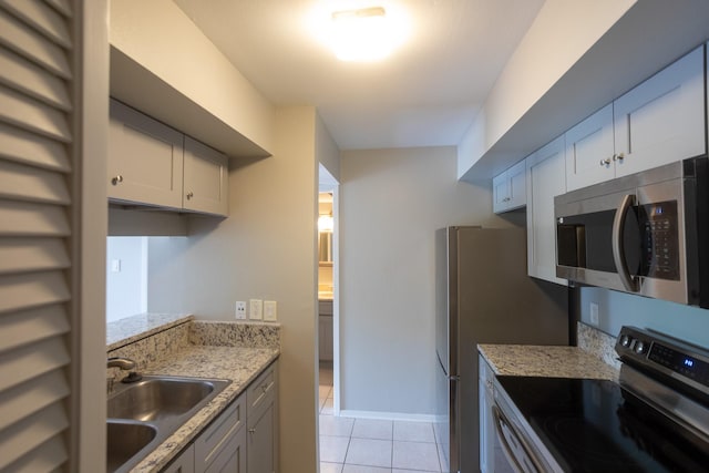 2025 Augusta Dr Unit 208, Houston, TX 77057 - kitchen featuring light stone counters, a sink, appliances with stainless steel finishes, baseboards, and light tile patterned flooring