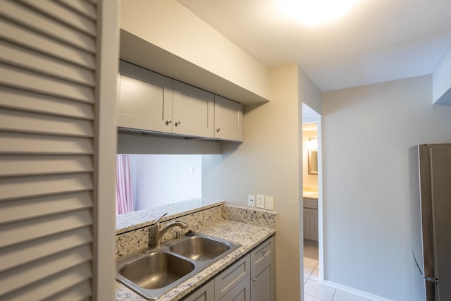 2025 Augusta Dr Unit 208, Houston, TX 77057 - kitchen featuring light stone counters, a sink, freestanding refrigerator, light tile patterned flooring, and gray cabinets