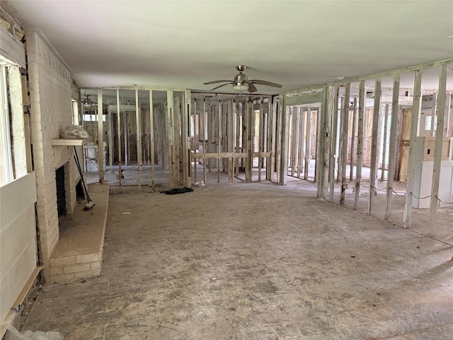 misc room with a brick fireplace and ceiling fan