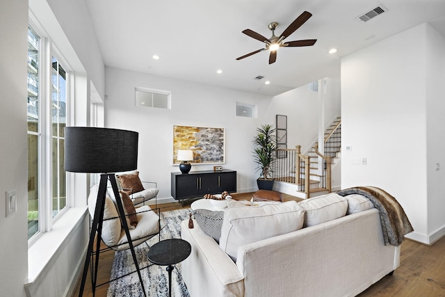 living area with stairway, a ceiling fan, wood finished floors, and visible vents