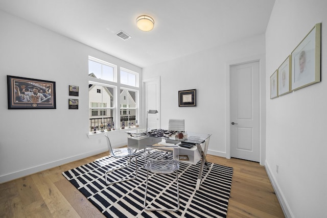 office area with light wood-style flooring, visible vents, and baseboards