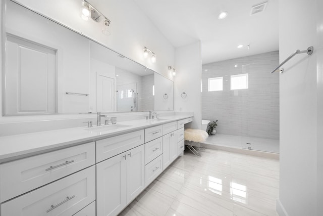 full bathroom with double vanity, a shower stall, visible vents, and a sink