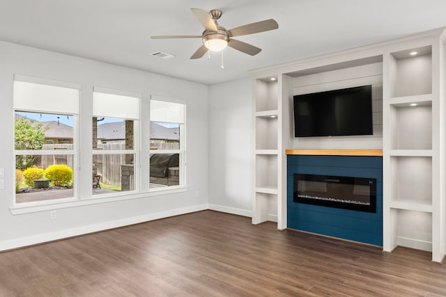 28928 Autumn Shore Dr, Fulshear, TX 77441 - unfurnished living room with wood finished floors, a glass covered fireplace, baseboards, a ceiling fan, and built in shelves