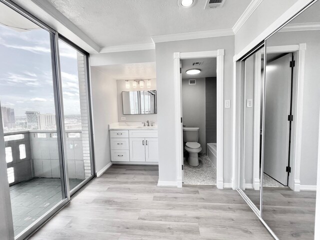 bathroom featuring wood finished floors, vanity, plenty of natural light, and crown molding