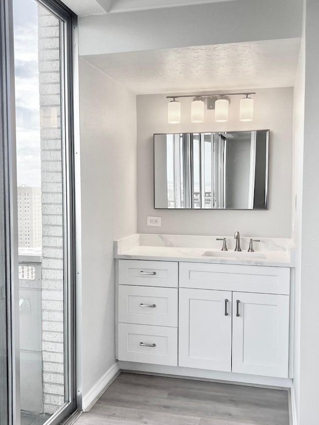 bathroom featuring vanity, wood finished floors, and baseboards