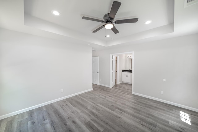 unfurnished bedroom with light wood-style floors, a raised ceiling, baseboards, visible vents, and recessed lighting