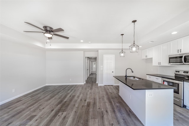 kitchen with dark countertops, a sink, ceiling fan, stainless steel appliances, and white cabinetry