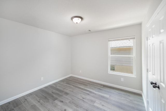 spare room with baseboards and wood finished floors