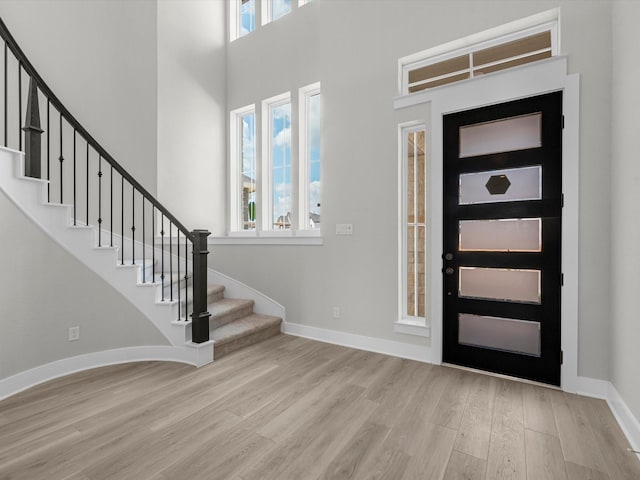 entryway with wood finished floors, a healthy amount of sunlight, baseboards, and stairway