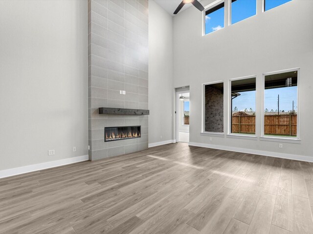 unfurnished living room with baseboards, wood finished floors, a fireplace, and ceiling fan