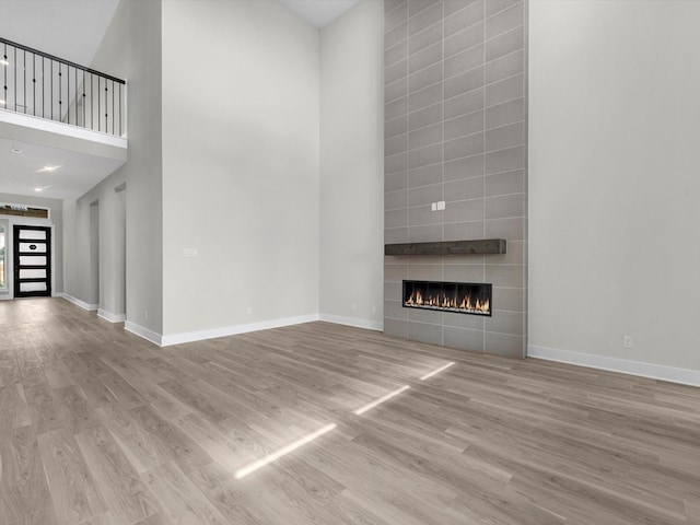 unfurnished living room featuring wood finished floors, a high ceiling, and baseboards