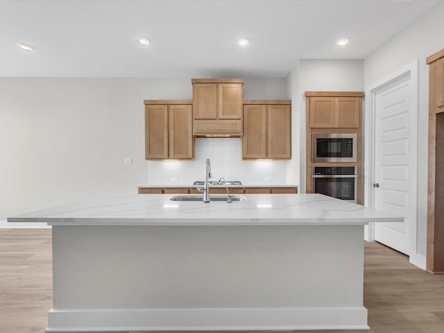kitchen with oven, light wood-style floors, built in microwave, and a sink