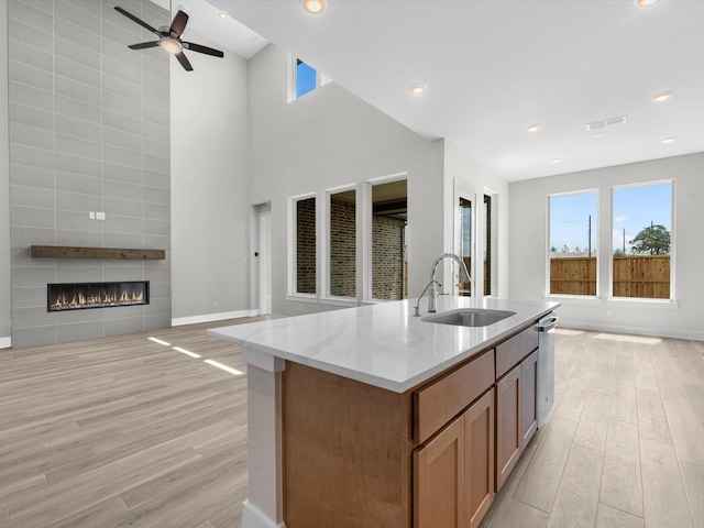 kitchen with light wood finished floors, open floor plan, stainless steel dishwasher, and a sink