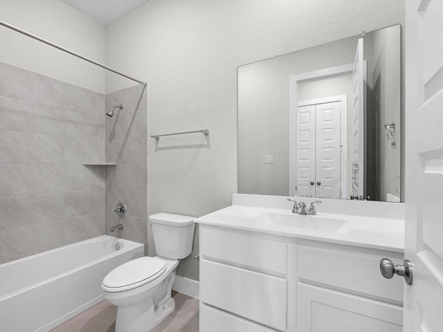 bathroom featuring toilet, vanity, washtub / shower combination, and baseboards